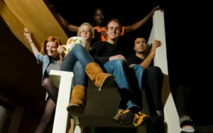Group of four visitors sitting on an oversized chair in the National Leprechaun Museum’s giant-sized room, experiencing a playful perspective illusion.