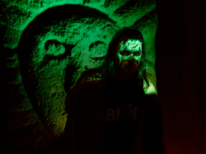 Green-lit folklore projection casts eerie patterns over a man at the National Leprechaun Museum, creating a mystical mythological atmosphere.