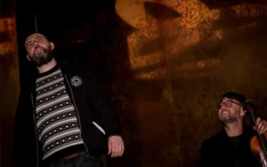 Storyteller performing alongside a musician in an atmospheric room during an Irish cultural event at the National Leprechaun Museum.