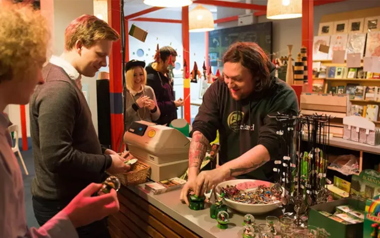 Visitors purchasing Irish folklore souvenirs at the National Leprechaun Museum gift shop, assisted by a smiling staff member.