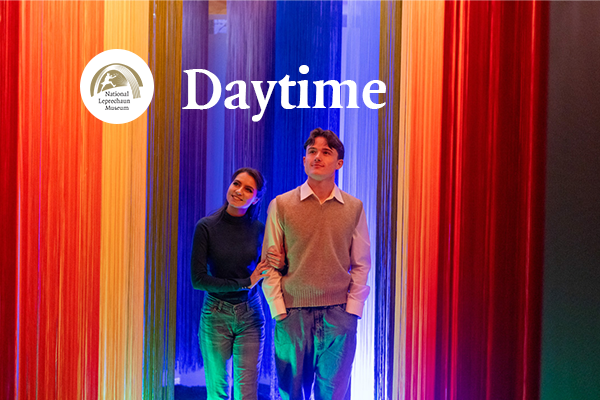 Yong woman and man walking through a rainbow-lit installation during the daytime experience, exploring colourful storytelling spaces inspired by Irish folklore.