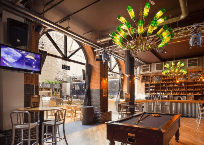 Vibrant bar area at Generator Hostel Dublin with unique bottle chandeliers, pool table and industrial-style décor.