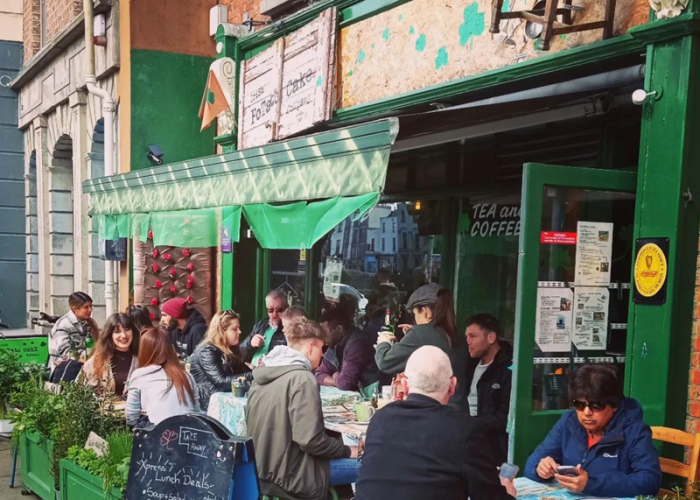 Outdoor diners enjoying meals at the Potato Cake Café in Dublin, with green awnings, rustic décor and a lively streetside atmosphere.