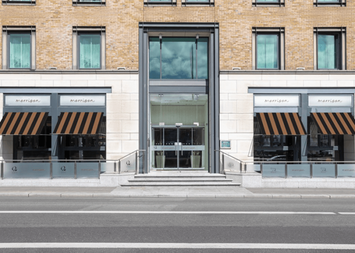 Front exterior of The Morrison Hotel in Dublin with striped awnings and modern glass entrance.