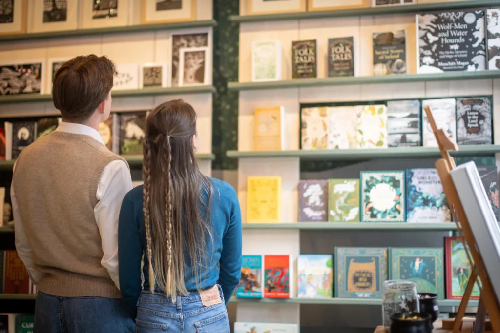 Young man and woman browsing shelves of Irish folklore books inside the National Leprechaun Museum’s storytelling-themed gift shop.