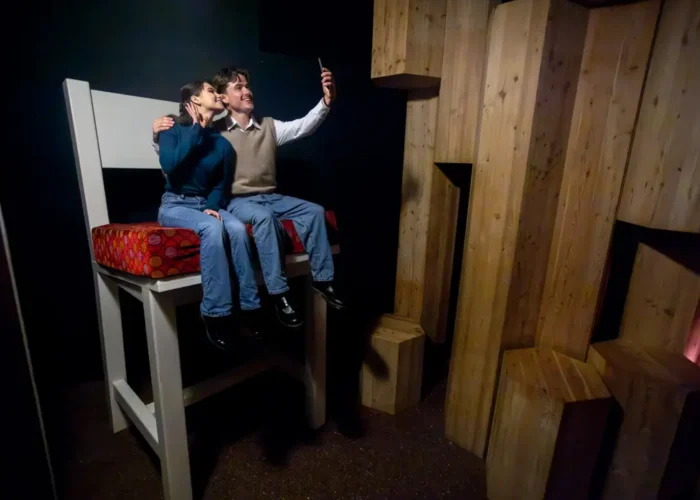 Man and woman taking a selfie while sitting on an oversized chair in the National Leprechaun Museum’s giant-themed room.