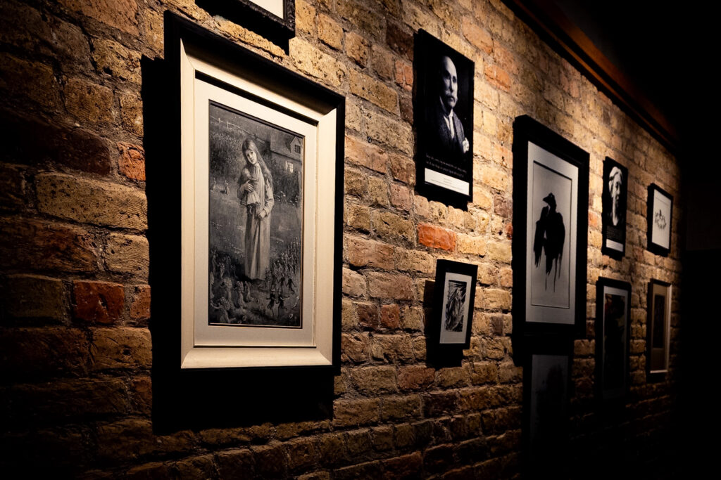 Various photos and drawings associated with Irish folklore are mounted on a brick wall.