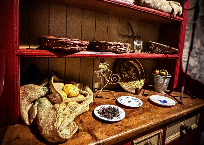An antique cabinet in a rustic cabinet. On the cabinet, plates have been laid out with small folk cures. A sack of potatoes sits beside them.